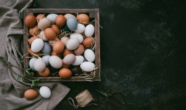 Paskalya yumurtalarının olduğu klasik bir arka plan. Eskimiş arka planda eski mutfak eşyaları. Yumurtalar ve bahar dalları ile Paskalya arkaplanı. Kopya alanı ile üstten görünüm.