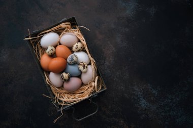 Paskalya yumurtalarının olduğu klasik bir arka plan. Eskimiş arka planda eski mutfak eşyaları. Yumurtalar ve bahar dalları ile Paskalya arkaplanı. Kopya alanı ile üstten görünüm.