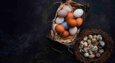 Paskalya yumurtalarının olduğu klasik bir arka plan. Eskimiş arka planda eski mutfak eşyaları. Yumurtalar ve bahar dalları ile Paskalya arkaplanı. Kopya alanı ile üstten görünüm.