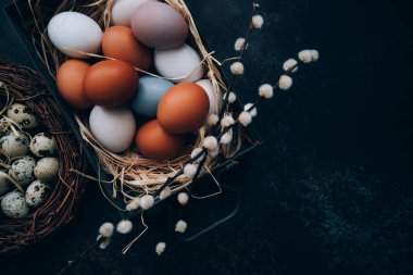 Paskalya yumurtalarının olduğu klasik bir arka plan. Eskimiş arka planda eski mutfak eşyaları. Yumurtalar ve bahar dalları ile Paskalya arkaplanı. Kopya alanı ile üstten görünüm.