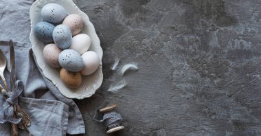 Koyu gri arka planda Paskalya yumurtaları olan klasik mutfak gereçleri. Kopyalama alanı olan üst görünüm.