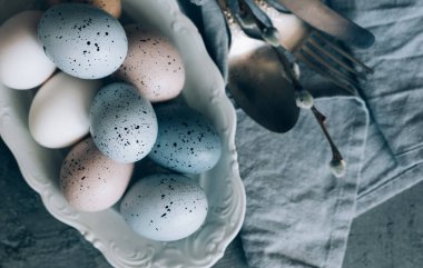 Koyu ahşap arka planda Paskalya yumurtaları olan klasik mutfak gereçleri. Kopyalama alanı olan üst görünüm.