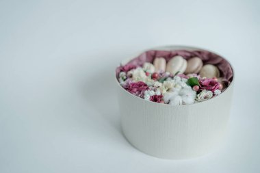 Gri arkaplanlı çiçek ve Fransız kurabiyeleriyle birlikte hediye ya da hediye. Kırsal tarzda. Tonu ayarlanmış resim.