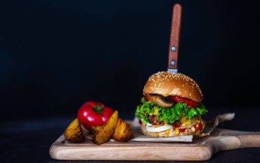 Sebzeli, mantarlı, marullu, domatesli, peynirli ve soslu taze sığır etli burger. Lezzetli ızgara ev yapımı hamburger. Fast food geçmişi.