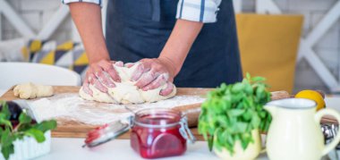 Kadın eli para kazanıyor. Un, yumurta ve diğer malzemelerle birlikte hamur, beyaz ahşap masada yatıyor. Ev yapımı pişirme işlemi.