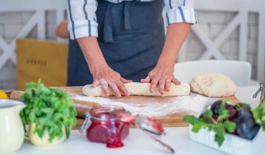 Kadın eli para kazanıyor. Un, yumurta ve diğer malzemelerle birlikte hamur, beyaz ahşap masada yatıyor. Ev yapımı pişirme işlemi.