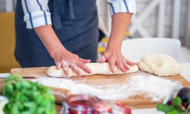 Kadın eli para kazanıyor. Un, yumurta ve diğer malzemelerle birlikte hamur, beyaz ahşap masada yatıyor. Ev yapımı pişirme işlemi.