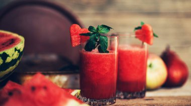 Kırsal ahşap arka planda karpuz. Sulu, olgun, kırmızı karpuz dilimleri. Taze meyve suyu. Kokteyl ve meşrubat. Tazeleyici yaz içeceği.