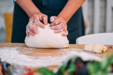 Kadın eli para kazanıyor. Un, yumurta ve diğer malzemelerle birlikte hamur, beyaz ahşap masada yatıyor. Ev yapımı pişirme işlemi.