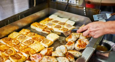 Yemek kamyonunda kızarmış börek yiyen bir kadın. Yemek kamyonu satıcısı müşteriye yemek servisi yapıyor. Asya sokak yemekleri, yemek servisi..