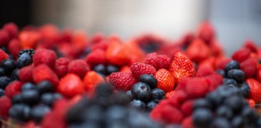 Çilek, yabanmersini ve ahududu karışımı renkli olgun böğürtlenler. Taze böğürtlenlerin geçmişi. Seçici odak.