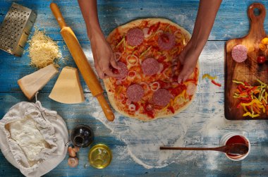 O pizza için malzemeler koyar