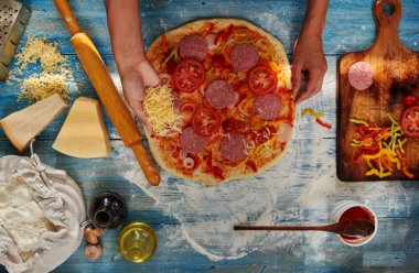 O pizza için malzemeler koyar