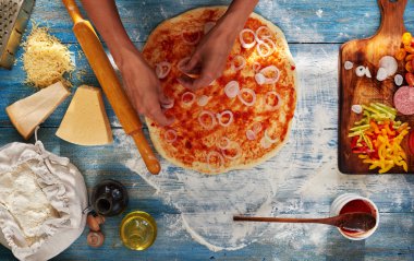 O pizza için malzemeler koyar