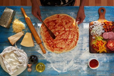 O pizza için malzemeler koyar