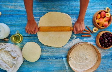 Young girl chef kneads  and rolling the dough with pin