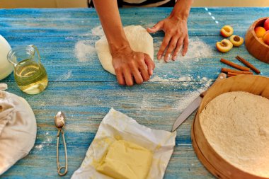 Young girl chef kneads  and rolling the dough with pin