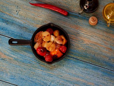 On the table is a frying pan with vegetables
