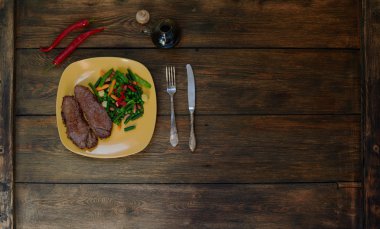 On the table is a bright plate with two pieces of meat