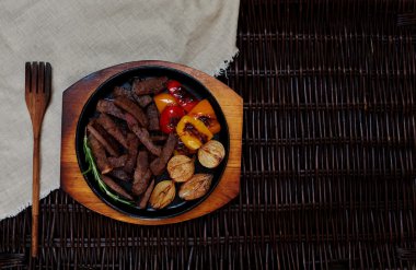 Fırında bir seramik pişirme çanağı içinde yatan et parçalar halinde kesilmiş