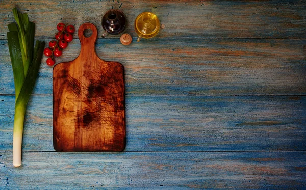 On the table is a blue wooden board for cutting vegetables — 图库照片