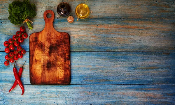 On the table is a blue wooden board for cutting vegetables — 图库照片