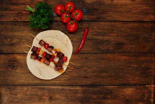 On the table is a plate with slices of bright meat on skewers — Stock Fotó