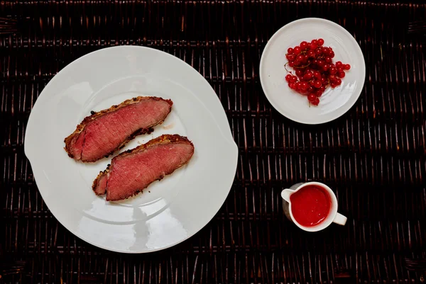İki kızarmış biftek yalan büyük bir beyaz tabak üzerine — Stok fotoğraf
