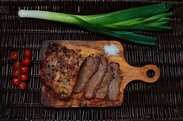 On the table is a wooden board on which the chef cut a piece of meat into portions
