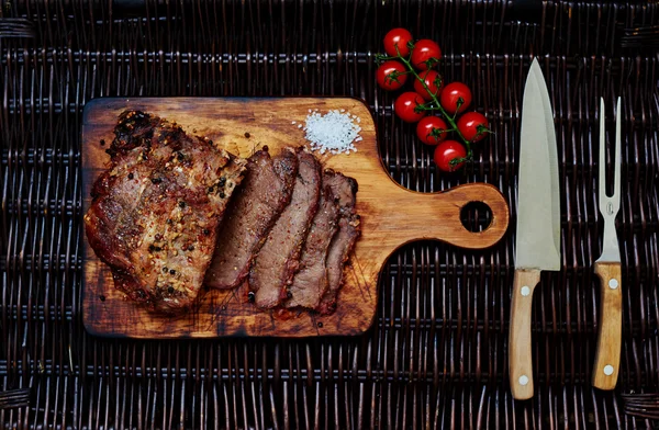 En la mesa hay una tabla de madera en la que el chef corta un trozo de carne en porciones — Foto de Stock