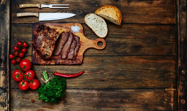 Na mesa está uma tábua de madeira na qual o chef cortou um pedaço de carne em porções. — Fotografia de Stock