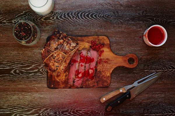 Na mesa está uma tábua de madeira na qual o chef cortou um pedaço de carne em porções. — Fotografia de Stock