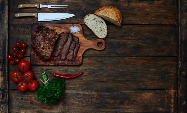 On the table is a wooden board on which the chef cut a piece of meat into portions — Stock Photo, Image