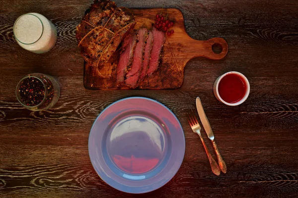 Auf dem Tisch liegt ein Holzbrett, auf dem der Koch ein Stück Fleisch in Portionen schneidet — Stockfoto