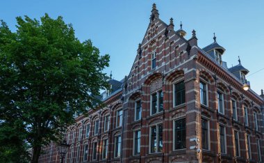 Hollanda, Amsterdam 'daki neo-gotik mimarinin çarpıcı bir örneği, bu tarihi köşe binasında basamaklar, kırmızı tuğla desenler, dekoratif pencere ayrıntıları ve dekoratif kuleler yer alıyor..