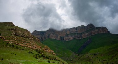 Baharda bulutlu ve yağmurlu bir gün, alçak fırtına bulutları. Bahar dağı manzarası. Vadinin muhteşem manzarası ve Georgia 'nın yemyeşil otlakları. Vadi yüksek sıradağlarla çevrili..