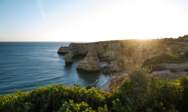 Золотые лучи заходящего солнца освещают скалы и спокойные прибрежные воды, заливая теплым светом пышную растительность и уединенные песчаные бухты этого живописного средиземноморского ландшафта..