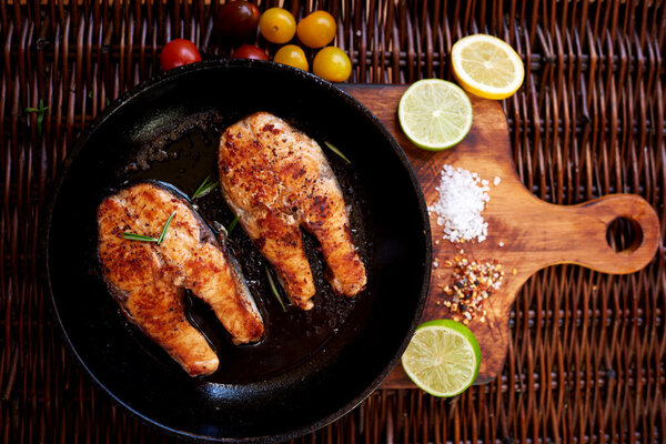 There are two salmon steaks in a frying pan