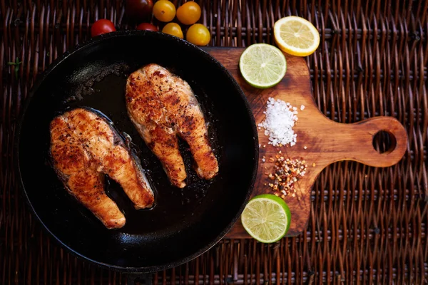 There are two salmon steaks in a frying pan