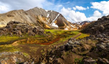 Karlı tepelerin, sarı volkanik tepelerin arasında dolambaçlı bir patikanın renkli manzarası. Brennisteinsalda Tepesi, İzlanda 'dan kırmızı kil ve yeşil yosunlar.