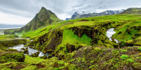 Manzaralı yüksek dağ Drangshildarfjall üzerinde geniş bir manzara Skogafoss şelalesi ve İzlanda 'nın güneyindeki eski sahil şeridinin kayalıklarında yeşil alanlar arasında akan Skoga Nehri manzarası..
