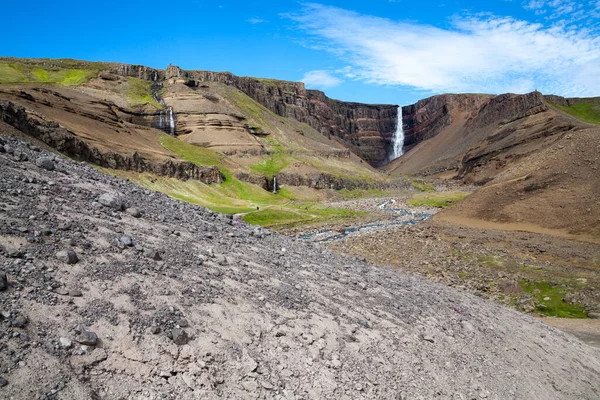 Pohoří a vysoký vodopád mezi skalami na Islandu. — Stock fotografie