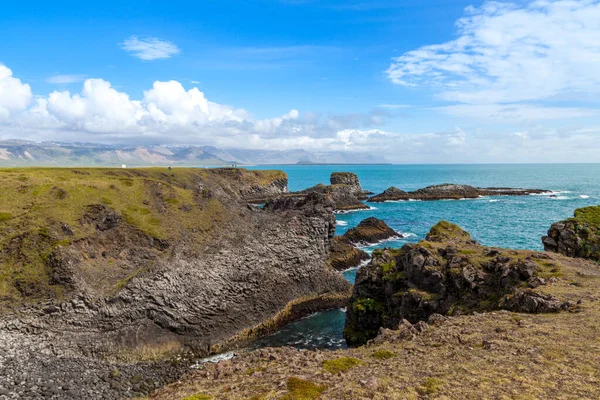 Letni krajobraz na skalnym wybrzeżu wulkanu nad turkusowym oceanem, Islandia — Zdjęcie stockowe