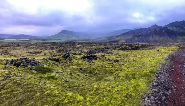 Lava Izland sziklák panoráma piros út és a régi vulkán hegy horizonton — Stock Fotó