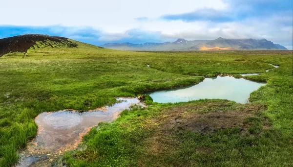 Aguas geotermales calientes entre el musgo verde contra el telón de fondo de montañas amarillas — Foto de Stock