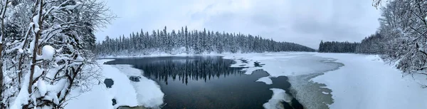 Panorama eines eisbedeckten Flusses inmitten eines gefrorenen Taigawaldes in einem strengen Winter — Stockfoto