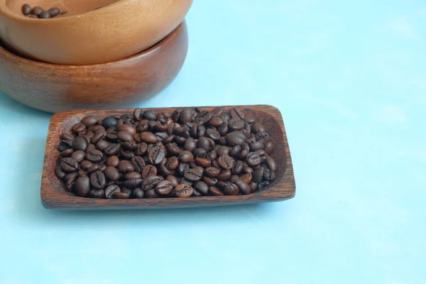 Granos de café asados en el plato de madera sobre un fondo azul — Foto de Stock