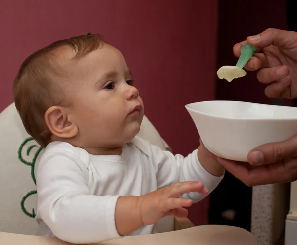 Criança pequena almoçando com uma colher — Fotografia de Stock