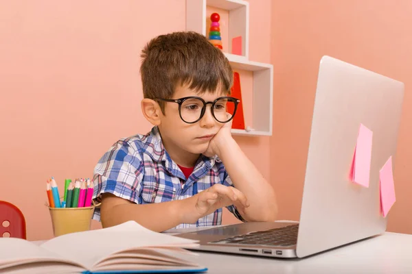 Child learning at home via virtual classes. Interactive content for primary online classroom. Home learning. Kid boy with headphones using laptop at table in room