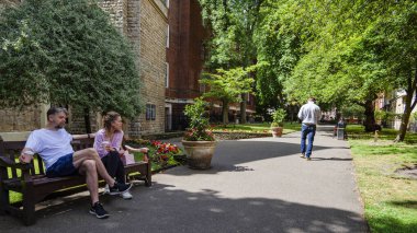 Londra - 07 03 2022: İnsanlar bankta oturuyor ve Mount Street Gardens 'ta yürüyor